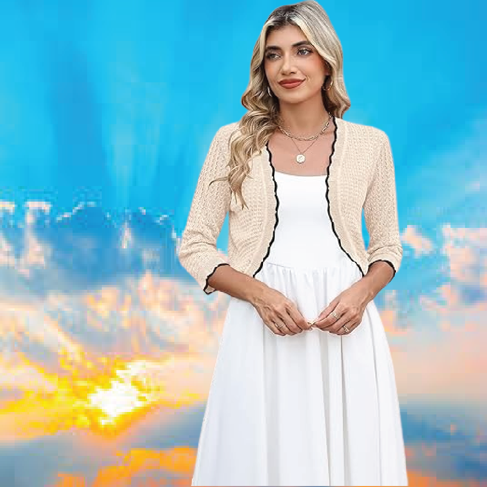 A woman wearing an elegant beige cropped knit cardigan bolero shrug over a simple white sleeveless dress.