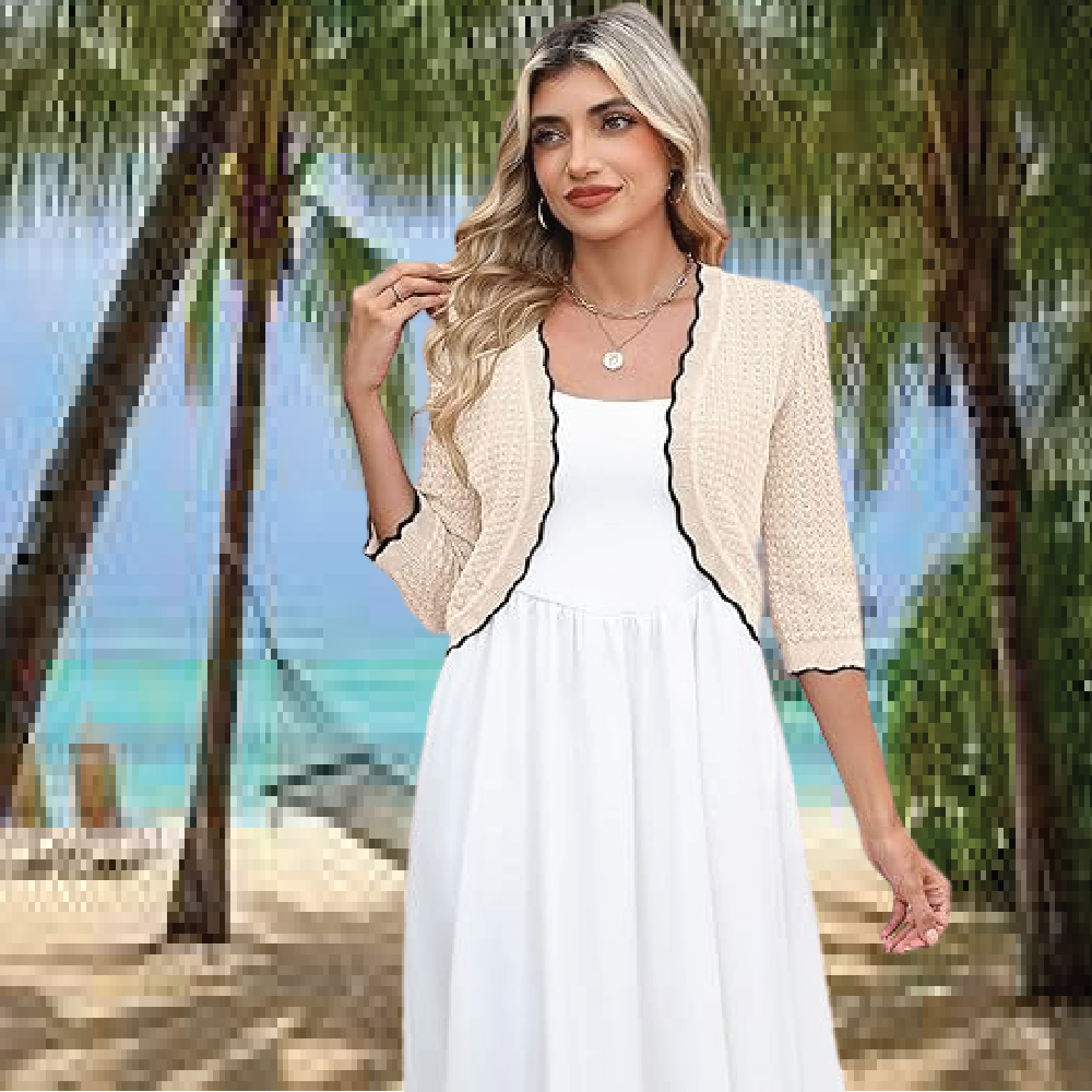 A woman wearing an elegant beige cropped knit cardigan bolero shrug over a simple white sleeveless dress.