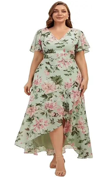 A model wearing a light green plus-size dress with a pink floral print, featuring a V-neckline, flutter sleeves, and an asymmetrical high-low hem with ruffle trim.