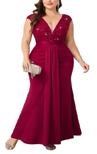A model wearing a floor-length burgundy plus-size gown featuring a sparkling sequin and lace V-neck bodice, short cap sleeves, and a draped skirt with tummy-control pleats.