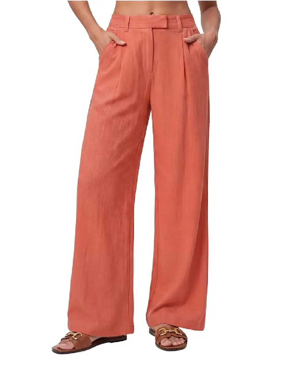 A woman wearing coral-colored high-waisted wide-leg pants with front pleats and side pockets, styled for a polished casual look.