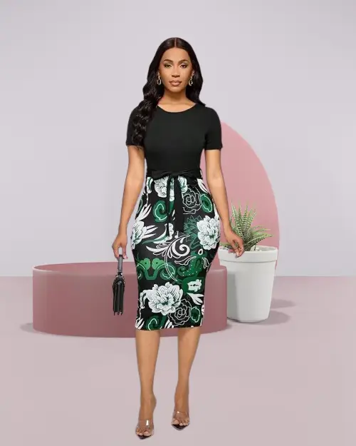 A woman wearing a black short-sleeved top with a floral print skirt and belt.