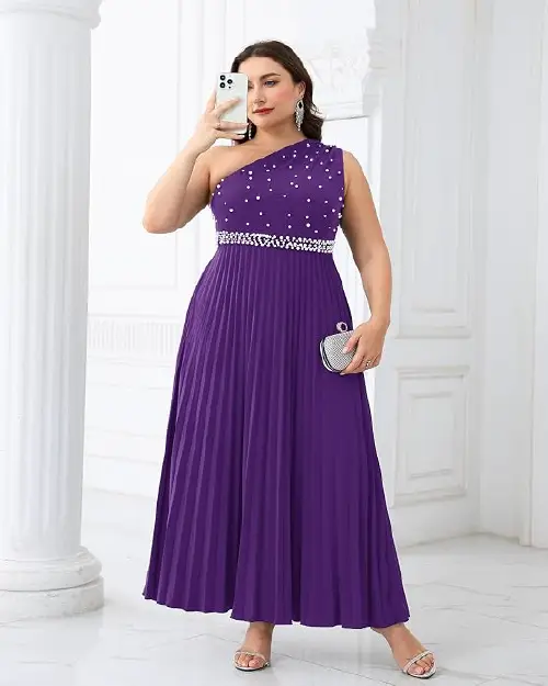 A woman wearing a purple one-shoulder pleated maxi dress decorated with pearl embellishments.