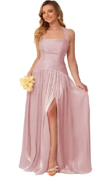 A woman modeling a dusty pink halter-neck bridesmaid dress with a ruched bodice, flowing A-line skirt, and a high side slit.