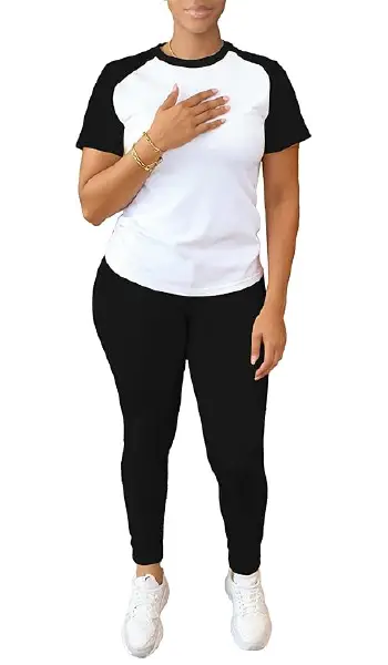 A woman modeling a black and white 2-piece outfit featuring a short-sleeve raglan tee with contrasting sleeves and matching black long pants.