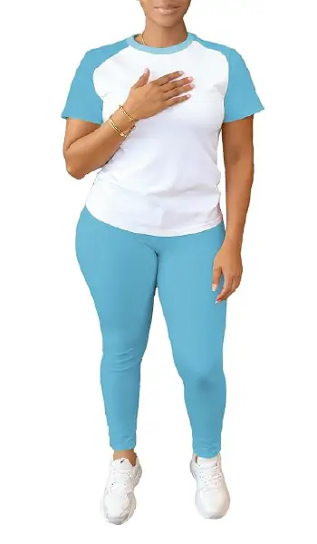 A woman modeling a black and white 2-piece outfit featuring a short-sleeve raglan tee with contrasting sleeves and matching black long pants.