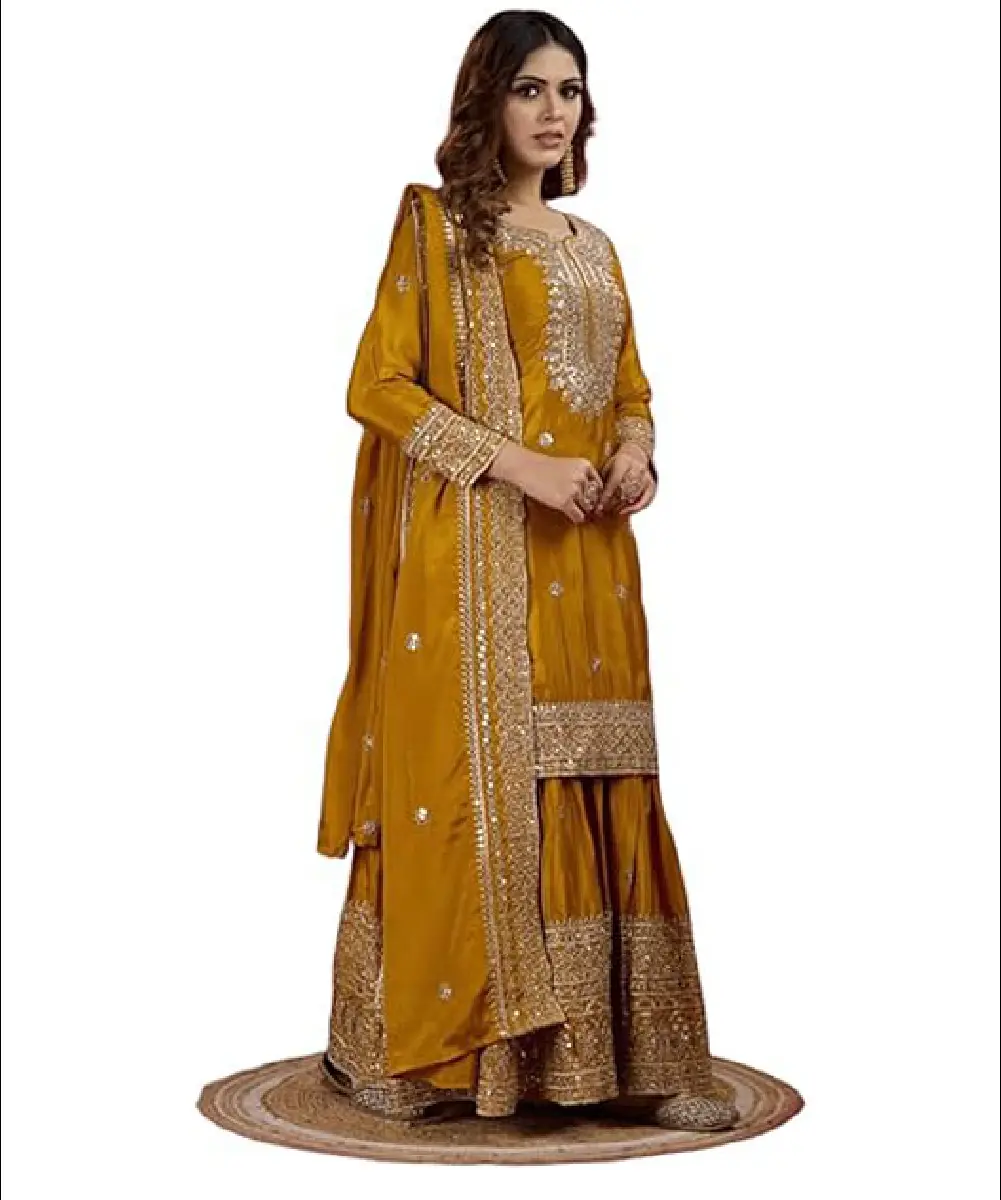 A model is wearing a heavy chinnon sharara suit and dupatta with mustard or dark yellow embroidery and sequin work.