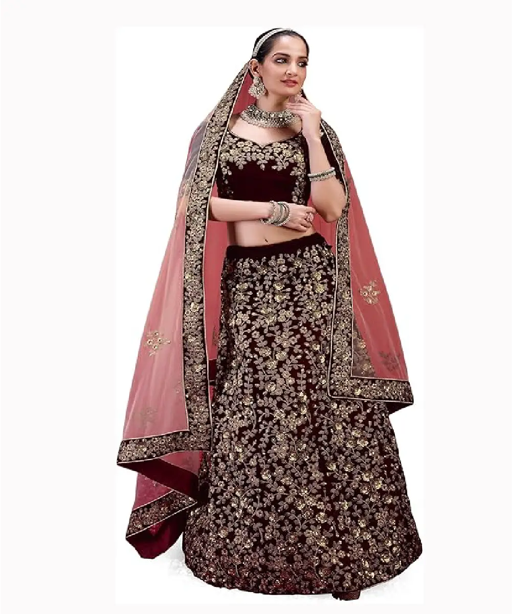 A woman is wearing a maroon velvet lehenga and a peach-colored net dupatta, which has heavy embroidery and sequin work.