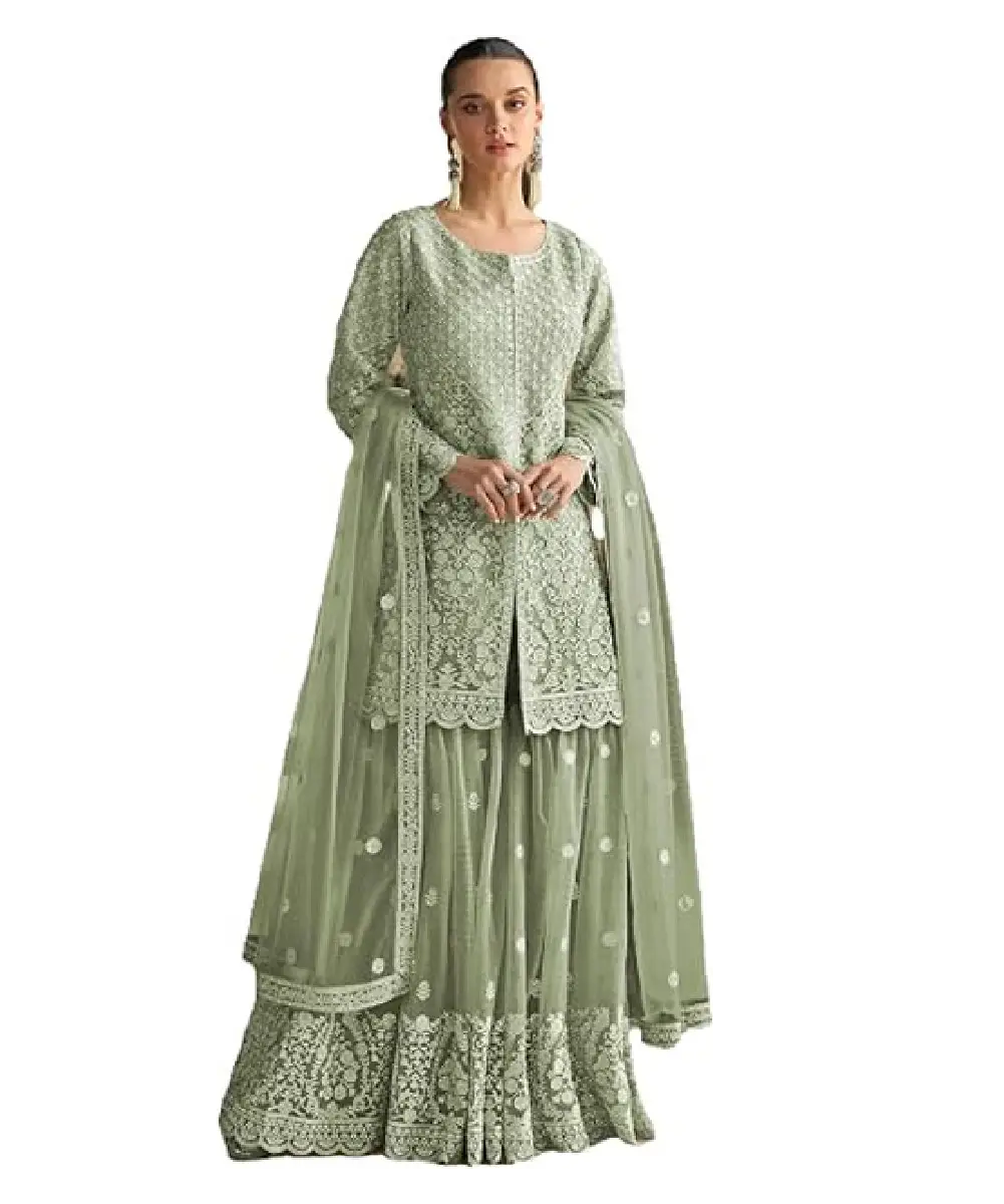 A woman wearing a sea green heavy net sharara suit featuring intricate sequin embroidery on the top, bottom, and dupatta.