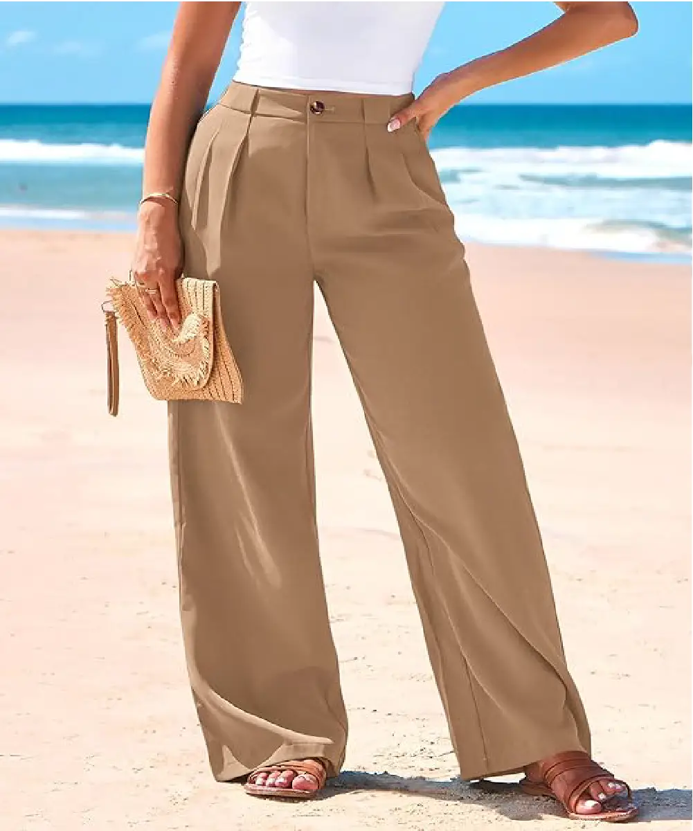 A woman wearing khaki high-waisted wide-leg palazzo pants with front pleats and a button closure, styled for a casual beach look.