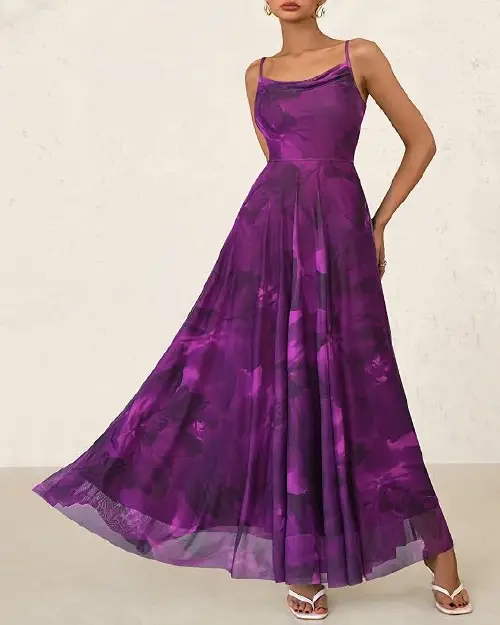 Woman wearing a rich purple abstract floral sleeveless maxi dress with a cowl neckline and flared hem.