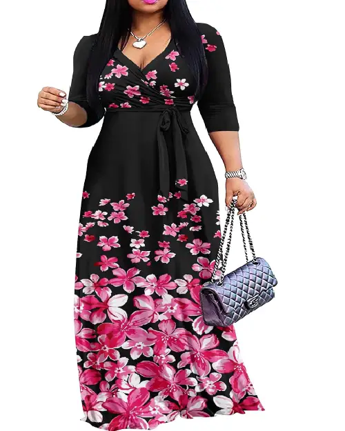 Woman wearing a black maxi dress featuring a cascading pink and white floral print gradient from hem to bodice, with a waist tie.