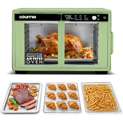Pastel green Gourmia family-size air fryer oven with French doors, accompanied by a tray of sliced steak with tomatoes, a wire cooling rack with croissants, and a basket of french fries.