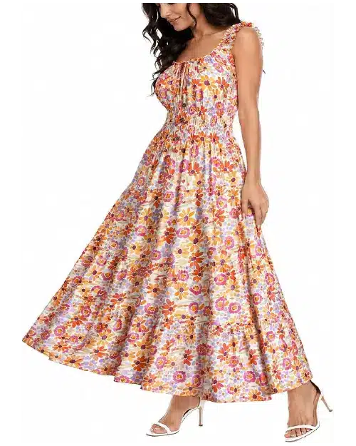 Woman wearing a sleeveless tiered maxi dress in a bright orange, yellow, and purple floral print with a smocked waist.