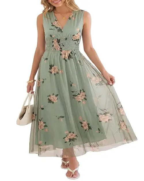Model in a sage green sleeveless maxi dress adorned with peach floral prints, featuring a smocked bodice and an ethereal mesh overlay.
