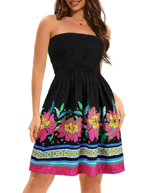 Woman wearing a black strapless smocked mini dress featuring vibrant pink floral prints and geometric border patterns around the hem.