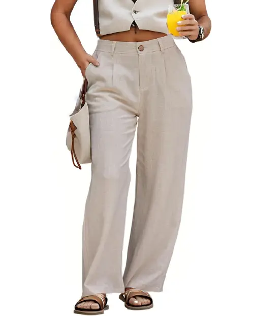 A person wearing beige high-waisted wide-leg work pants for women with front pleats and side pockets, paired with a matching vest, sandals, and a handbag.
