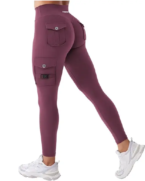 A person wearing berry purple high-waisted athletic leggings for women featuring side utility cargo pockets with button and buckle accents.