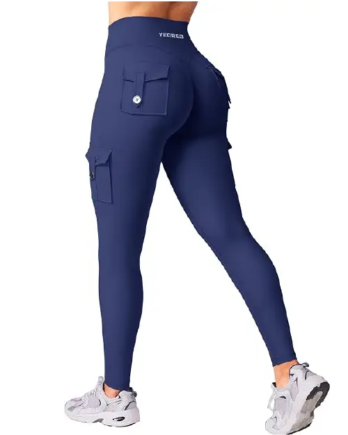 Navy blue high-waisted active cargo leggings for women featuring buttoned utility pockets on the back and sides, paired with grey sneakers.