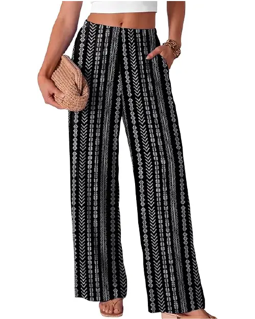 Black and white patterned wide-leg pants for women featuring a geometric ethnic print, high waist, and side pockets, paired with a white top and a woven clutch.