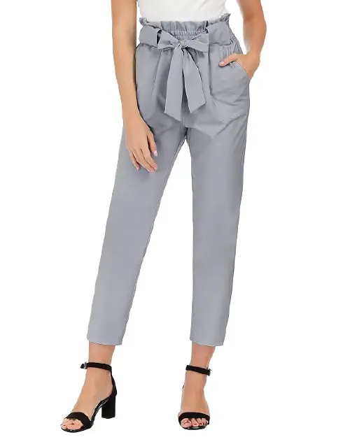 Light grey paperbag waist trousers for women featuring a self-tie bow belt, elasticated ruffled waistband, and tapered ankle cut, paired with black heeled sandals.