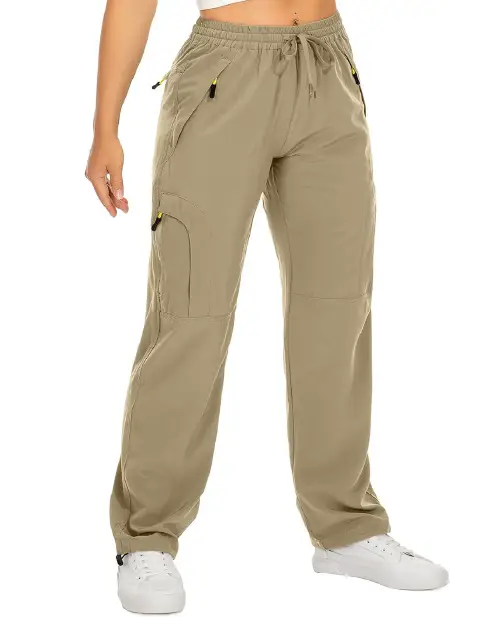 Light khaki active cargo pants for women featuring an elastic drawstring waist, side pockets with zipper details, and a relaxed fit, paired with white sneakers.