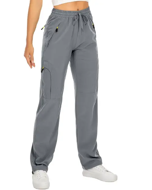 Grey active cargo pants for women featuring an elastic drawstring waist, multiple utility pockets with contrast zipper pulls, and a straight-leg fit, paired with white sneakers.