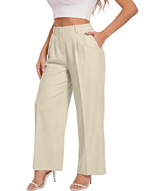 A person wearing light cream-colored high-waisted wide-leg work pants for women with front pleats and side pockets, paired with clear strap high heels.